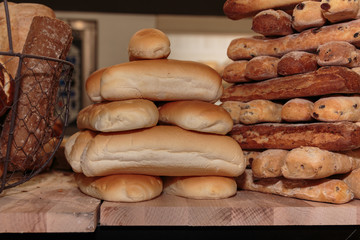 Heap of Bread Rolls Assortment and French Loaf on Wooden Board