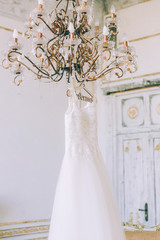 Wedding dress on the chandelier. Morning of the bride
