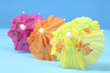 Multi-colored cocktail umbrellas on a blue background.