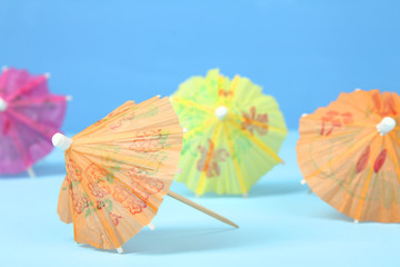 Multi-colored cocktail umbrellas on a blue background.