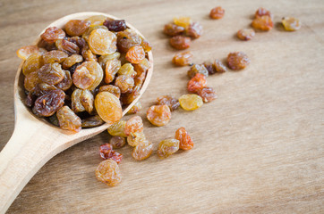 Dried Organic Raisins in a wooden Spoon on Rustic Background.