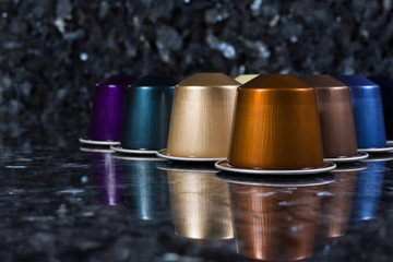 Cápsula de cafetera de varios colores sobre fondo oscuro