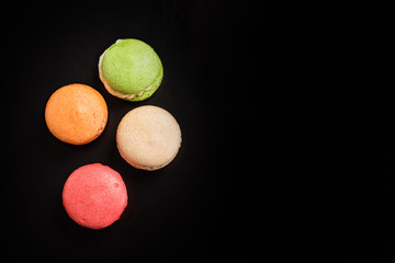 Multicolored macaroons falling or flying isolated on black background. Free space for text