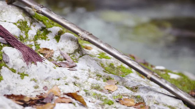 Traditional martial arts sword lying on stone rock with river in background 4K
