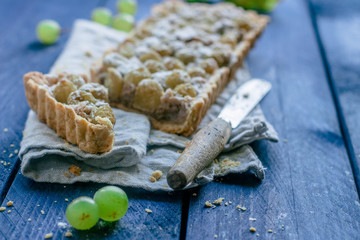 Walnut cake with grapes on wooden table background. Fruit tart
