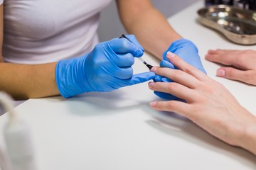 Obraz na płótnie Canvas Professional beautician applying nail polish to female nail