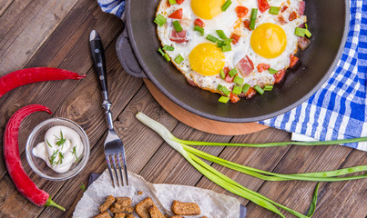 Fried eggs in pan with tomatoes and green fresh onion.