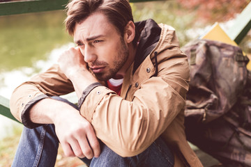 Fototapeta premium Thoughtful man sitting near river