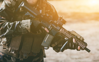 The soldier in the performance of tasks in camouflage and protective gloves holding a gun. The zone...
