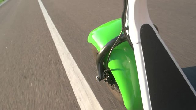 Fat wheel scooter and road. Asphalt and sunlight. Tires of top quality.