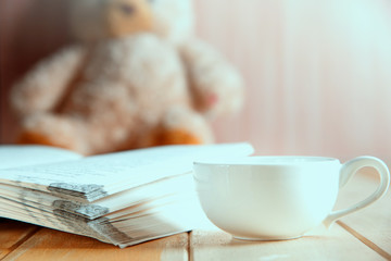 coffee cup and book focused on teddy bear in Blurred background