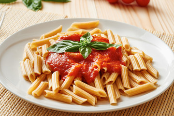 Pasta with tomato sauce and basil on white dish