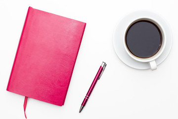 pink notebook with pen and a Cup of black coffee on white background. business minimal concept for women. Flat lay, top view.