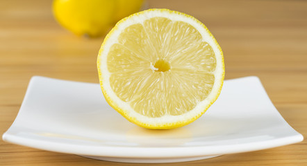 Eine halbe Zitrone auf einem weißen Teller in Nahaufnahme