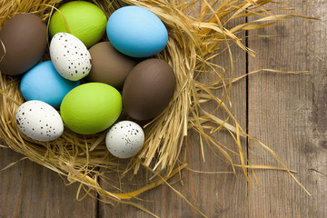 Easter eggs on wooden background in the nest. Top view