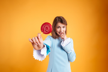 Pretty cute young woman giving you red lollipop