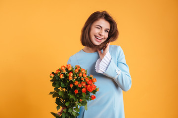 Happy playful young woman winking and holding bouquet of flowers