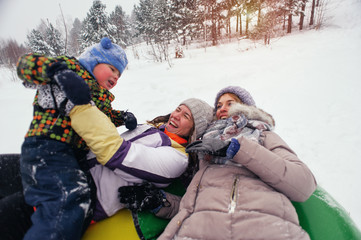 Fototapeta na wymiar Happy caucasian people hugging on snow tube