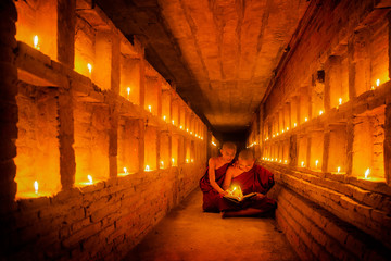 Young Buddhist Monk are reading a book with light from candle