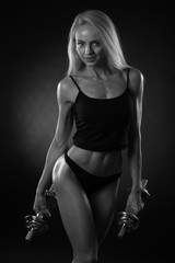 sporty muscular woman working out with dumbbells