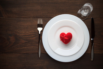 Romantic table setting for Valentines day with red heart on a plate.