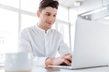 Man sitting near cup of coffee while using laptop