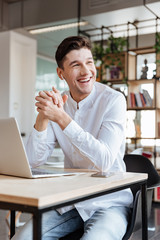 Handsome man using laptop computer while listening music
