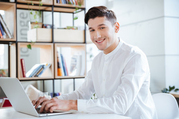 Happy man in white shirt using laptop computer
