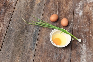 Raw egg in a bowl selective focus and onion on wooden table