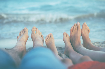 Three pairs of feet on the sand. Family on vacations.