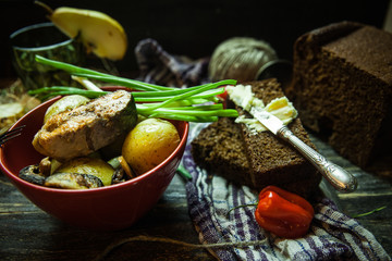 grilled salmon steak with potatoes, leak, peppers, butter on wooden table with napkin and fork