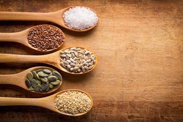 Food ingredients in wooden spoon on wooden background. Flax, pumpkin seed, sunflower seed, sesame and himalayan salt