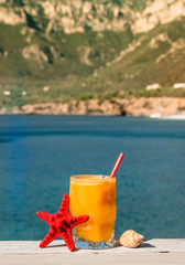Fresh orange juice on the seaside background.
