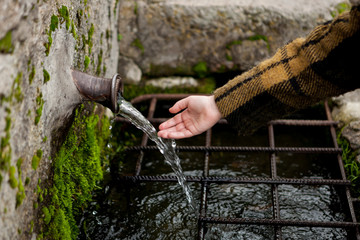 Hand touching water from a natural fountain