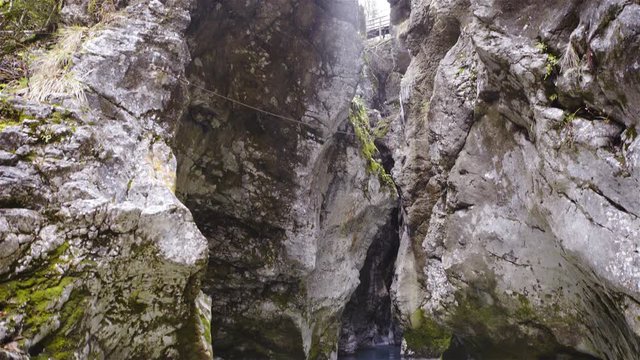 Kamniska Bistrica river flowing between mountain rocks tilt-shot 4K
