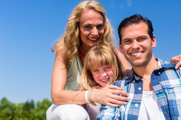 Girl on dads lap, Mom sitting next to them in field