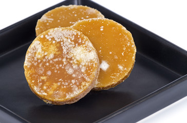 Sliced brown coconut sugar on black dish