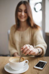 Woman stir sugar spoon in cup of cappuccino in cafe