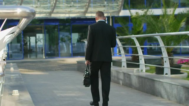 Businessman enters the office building holding a briefcase