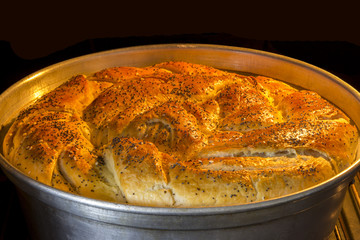 Round loaf of bread on stainless tray baking in oven