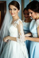Naklejka premium Bride looks thoughtful far away while bridesmaids fix her dress