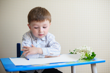 Naklejka premium little boy sitting at a desk and listening to the teacher