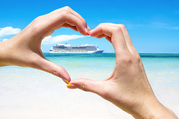 Cruise vacation concept. Cruise ship in the sea near the tropical island inside hands making heart shape. Tropical Resort. Vacation concept. Summer holidays. Tourism.  - obrazy, fototapety, plakaty