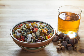 Ukrainian kutia and uzvar. Traditional christmas cereal wheat porridge with raisins, nuts, poppy seeds, honey and candied fruit in earthenware bowl with dried fruit drink on natural wood table