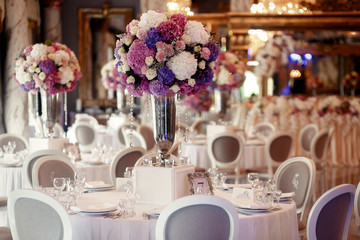 Round dinner table decorated with pink and violet hydrangeas sta