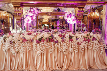 Dinner table covered with long beige cloth and decorated with fl