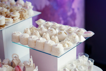 White sweets stand served on glass plate on white cube