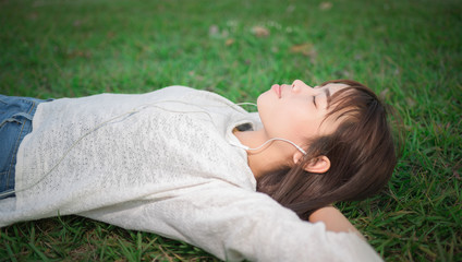 Relaxed woman listening to the music with earphone lying on the
