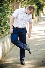 The young and handsome man looking at his dirty shoe on street. Dog shit on man's shoe.