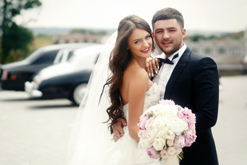 Groom holds bride's waist tender while she lies her arm on his s